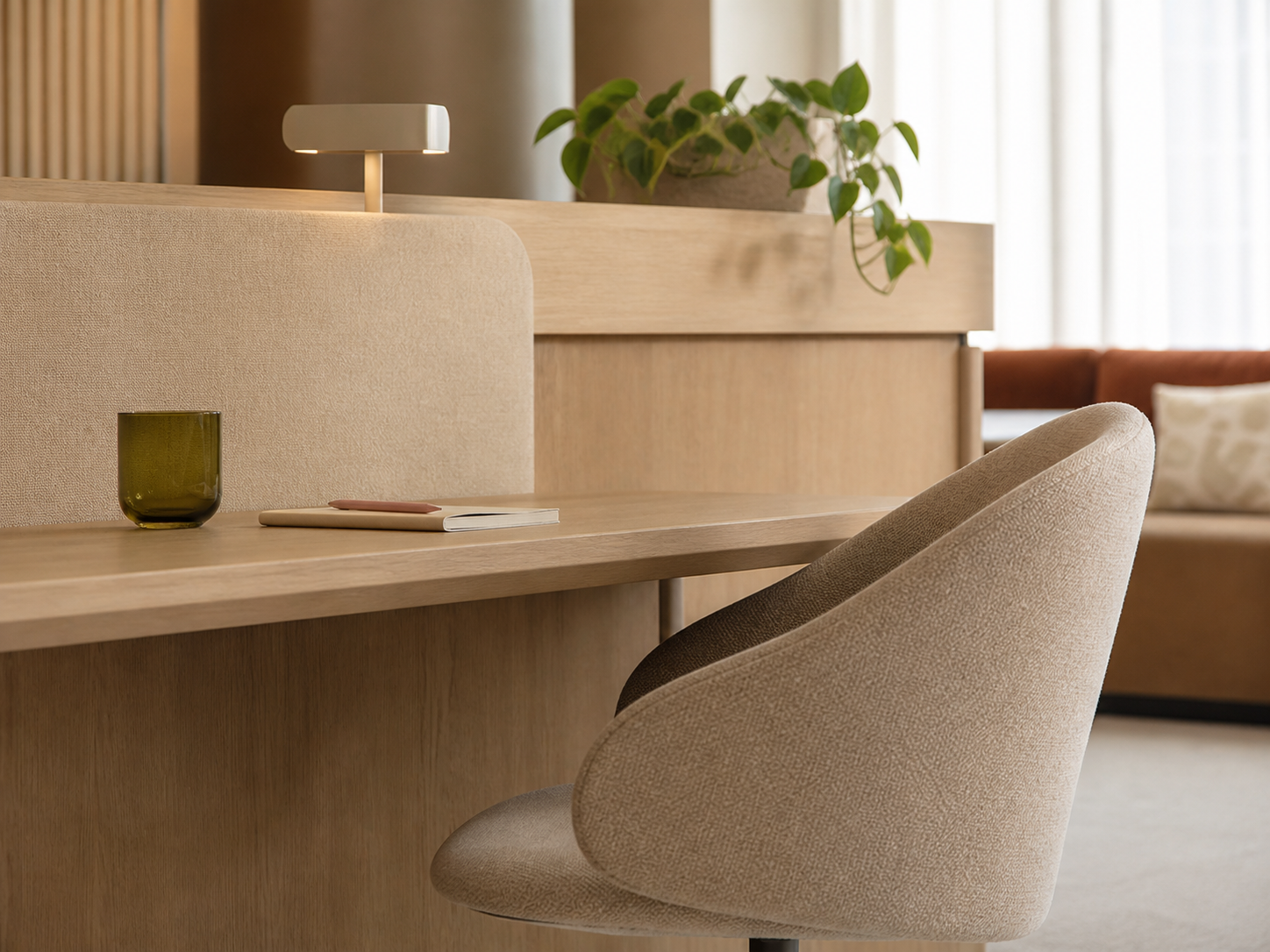 Minimalist beige workspace with a desk, chair, lamp, and potted plant by a window