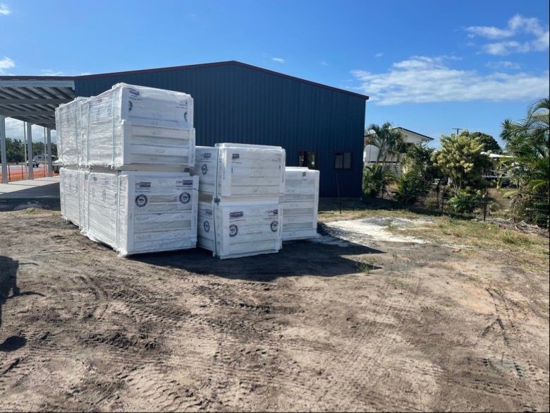Stacked White Wrapped Pallets Outside a Dark Warehouse — Les Carman Cooling Solutions in El Arish, QLD
