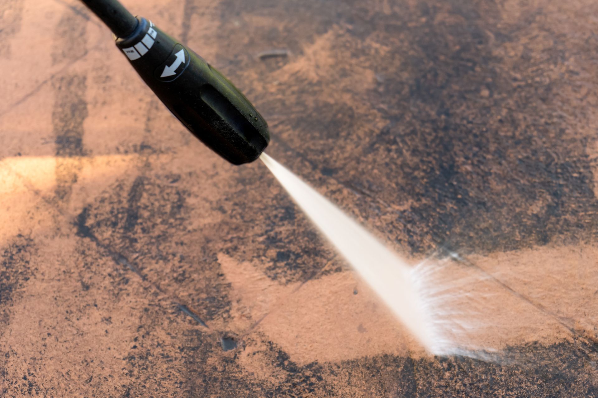A high pressure washer is spraying water on a concrete surface.