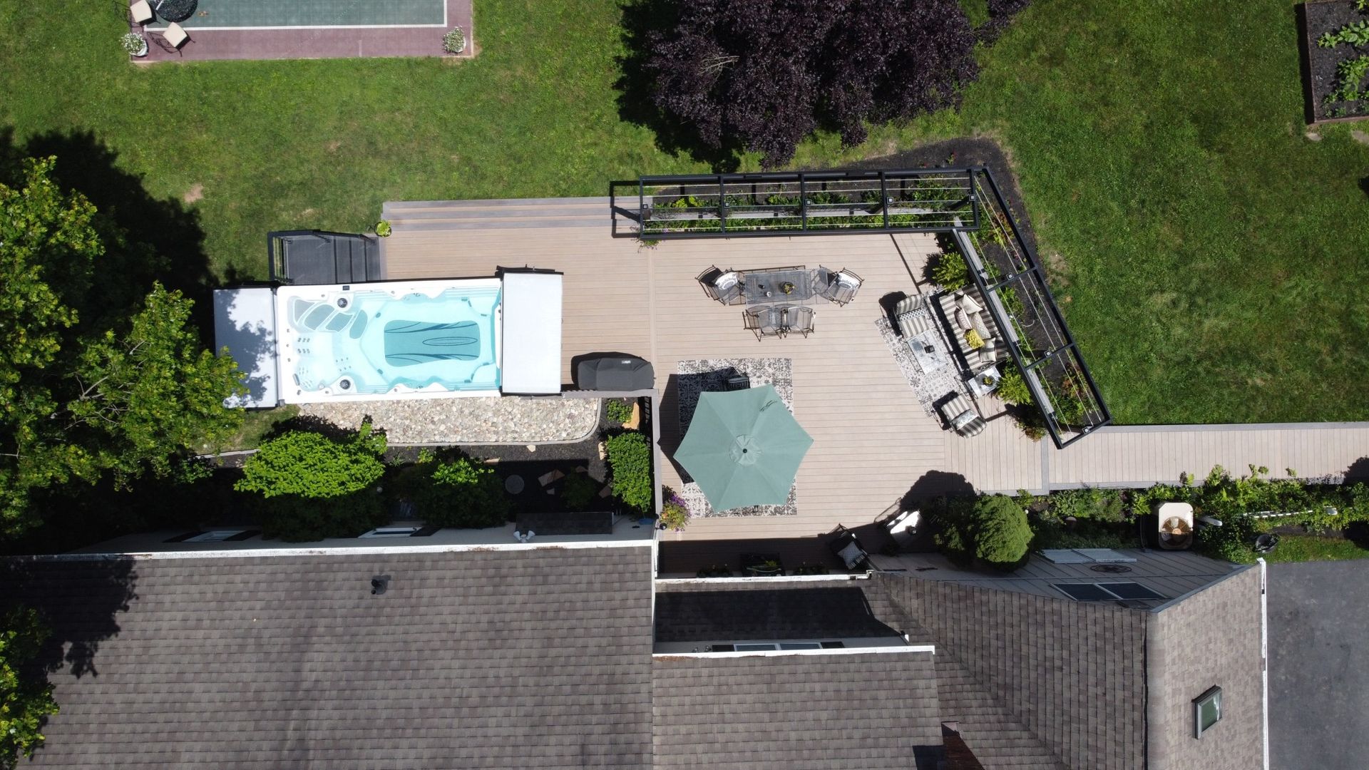 Overhead view of a backyard with a pool, deck, patio furniture, and garden.