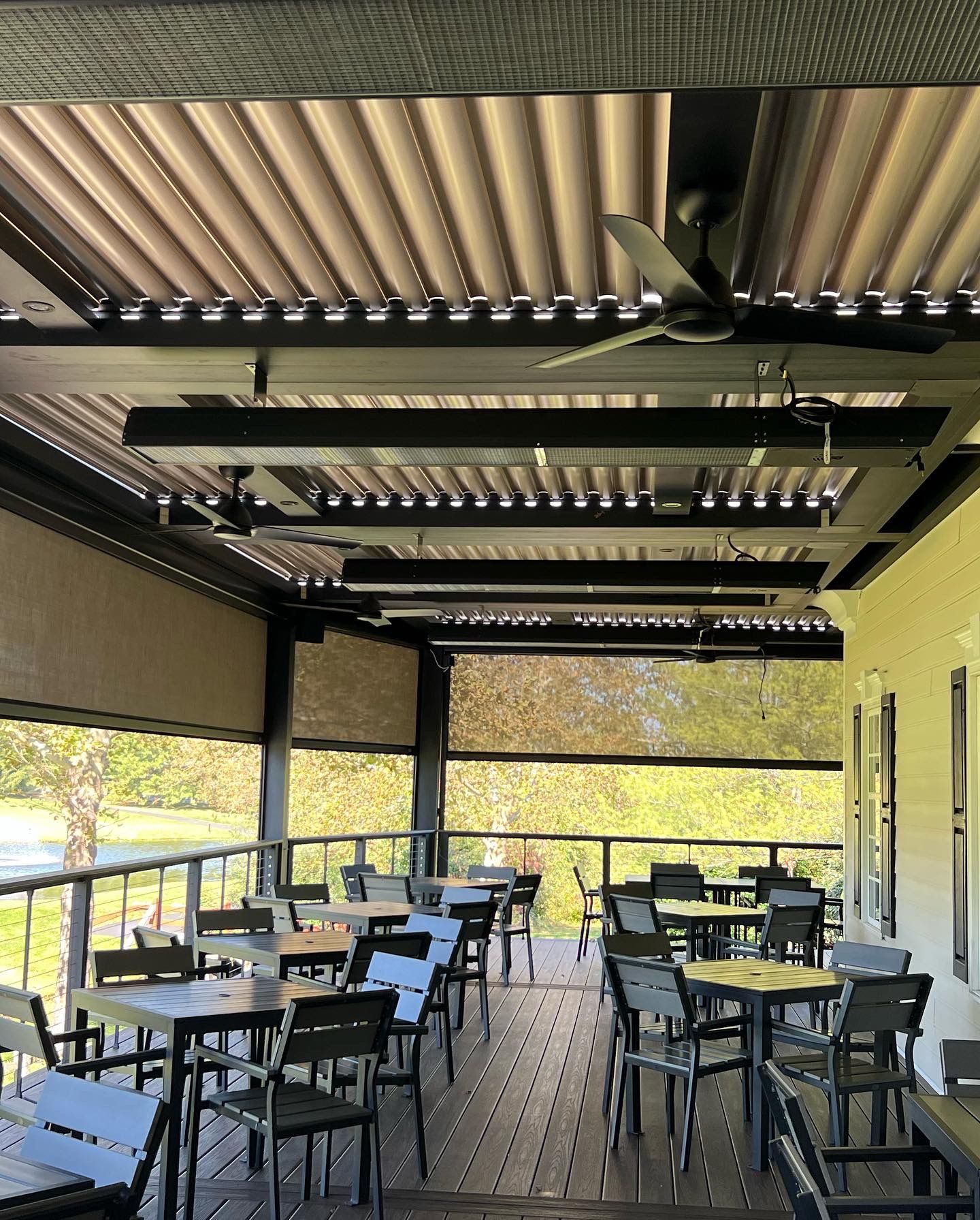 Outdoor dining area with tables, chairs, and a covered patio with fans and lights.