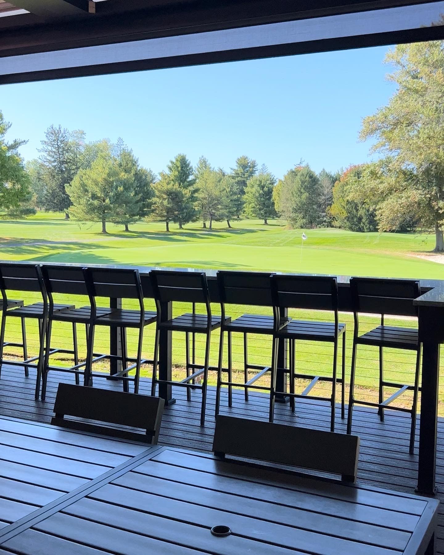 Outdoor seating area overlooking a green golf course under a blue sky.