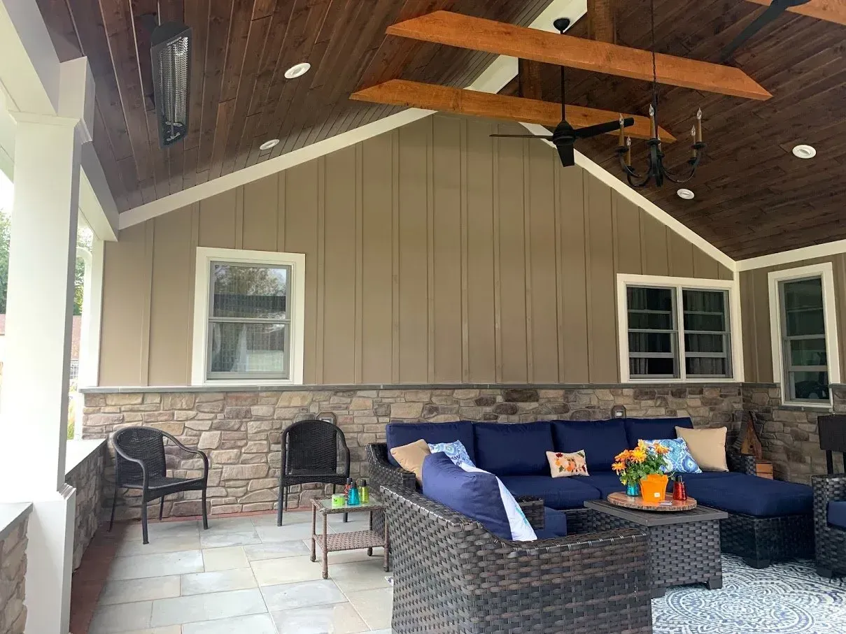 Outdoor patio with blue furniture, stone accents, and brown walls and ceiling.