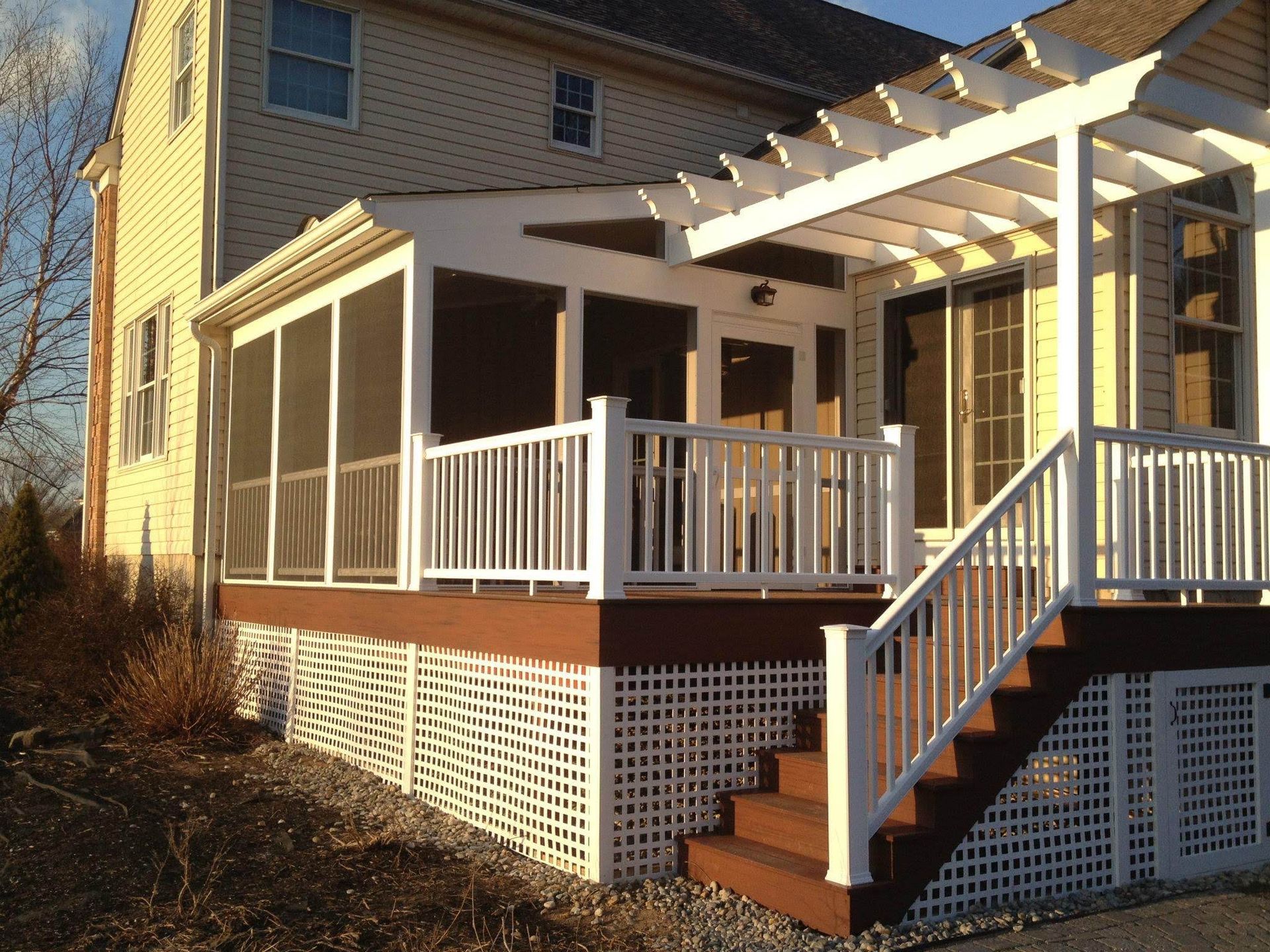 White deck with screen porch, stairs, and pergola. Brown deck boards, lattice, and siding.