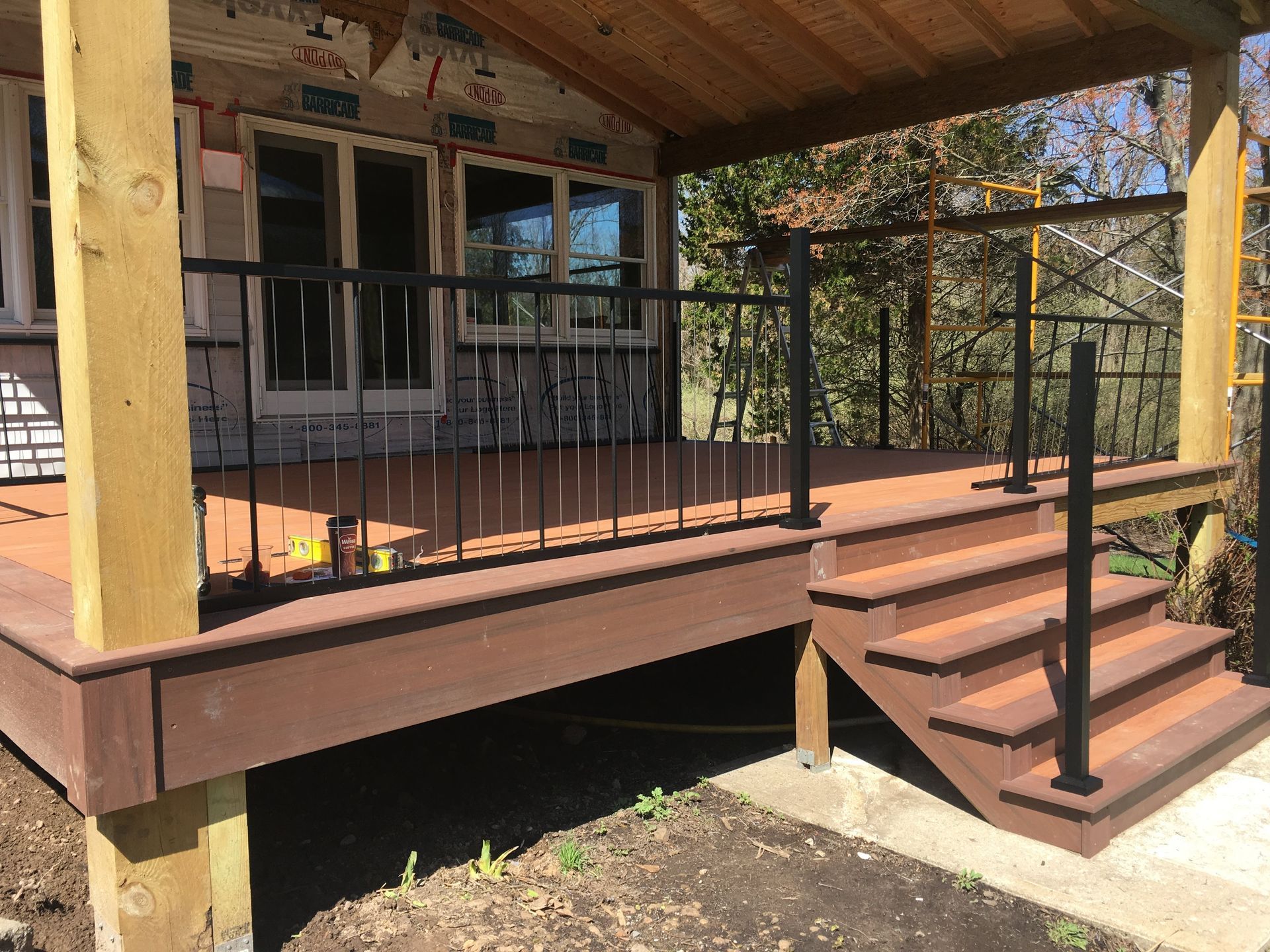 Brown wooden deck with black railings and steps leading to a house.
