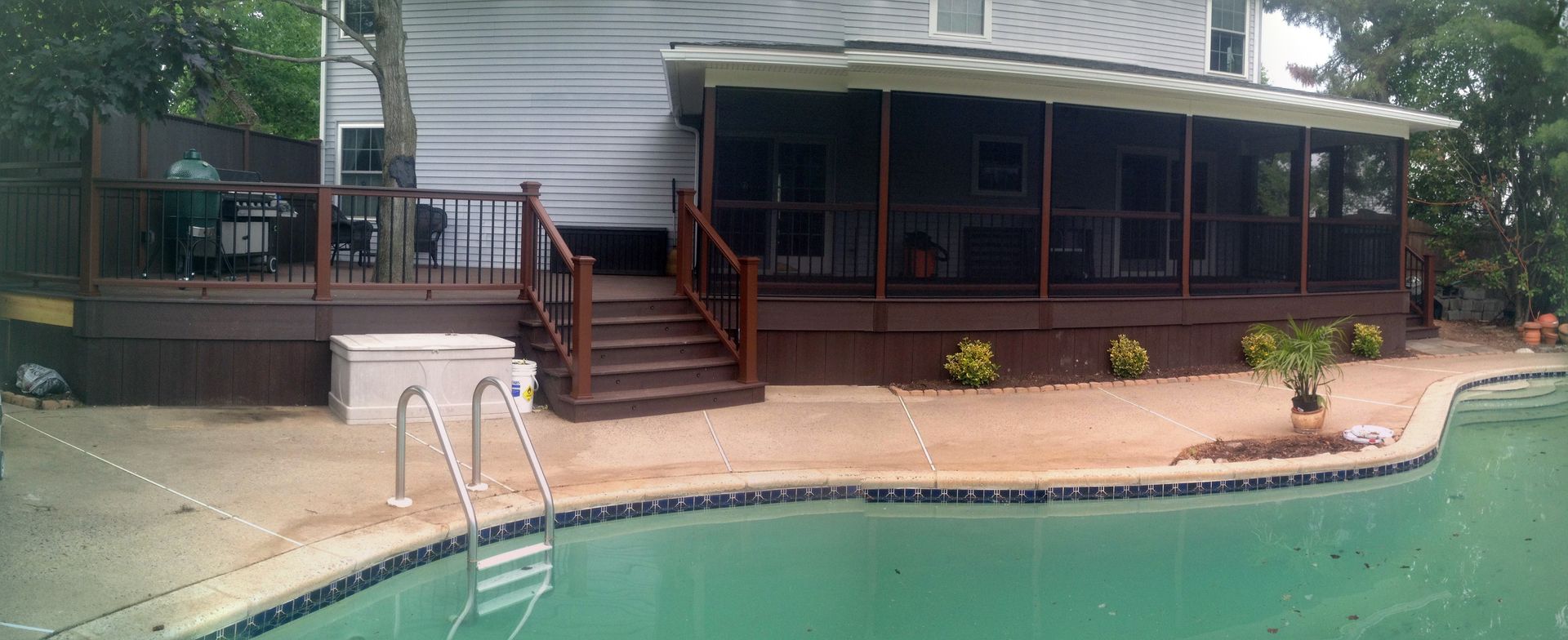 Backyard with a pool, deck, screened porch, and landscaping.