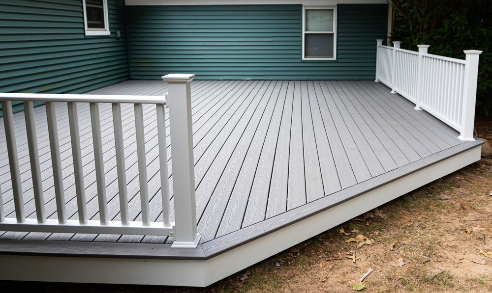 Gray composite deck with white railing, built against a teal house.