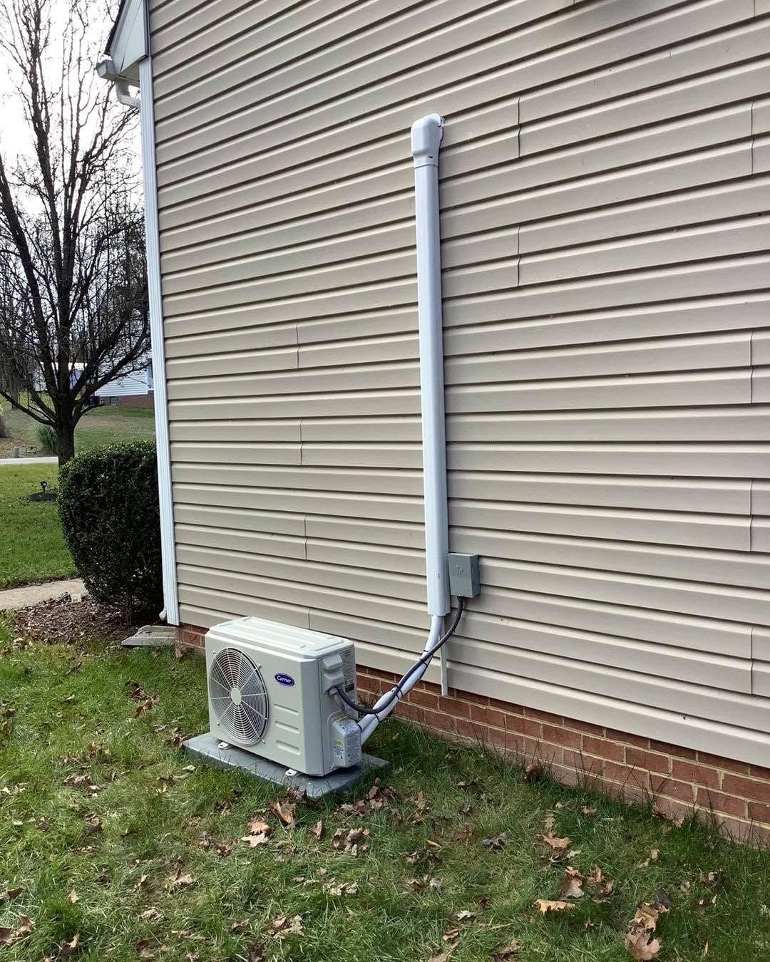 Outdoor air conditioner unit beside beige house siding and a white vent pipe