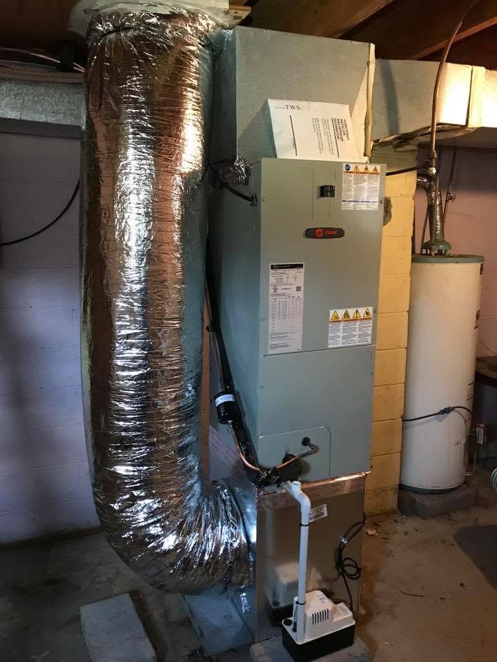 Basement HVAC unit with insulated ducting and a condensate pump beside it