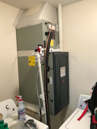 Utility closet with electrical equipment, cables, and a tall black cabinet against a white wall.