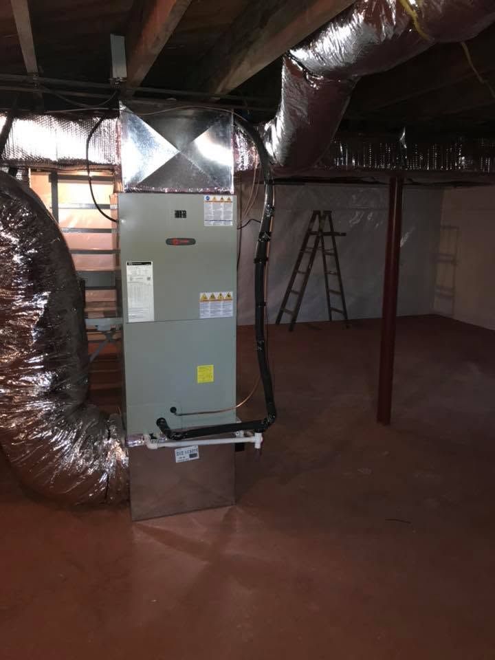 Basement HVAC furnace with silver ducts and ladder in a utility room