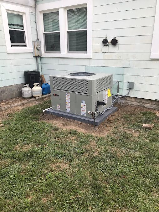 Gray outdoor generator on a concrete pad beside a house with white siding.
