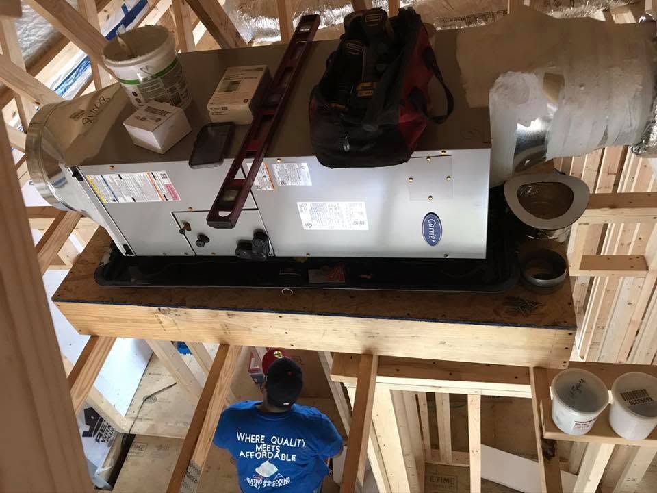 Two people in a wooden attic building a white rectangular box with tools and supplies on a shelf.