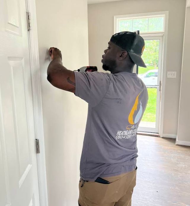 Worker painting a white door frame in a bright hallway near a front door.