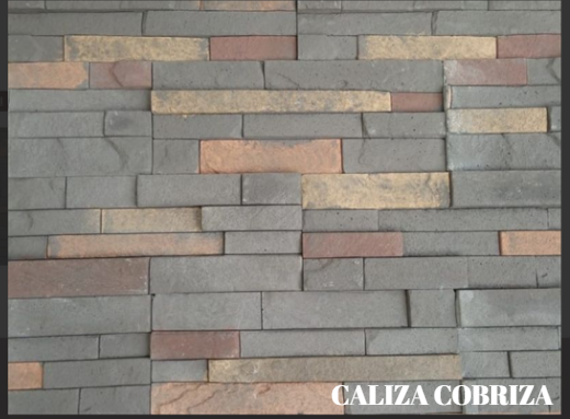 Muro de piedra apilada de colores en tonos beige, tostado y rojo con una pequeña etiqueta que dice “CALIZA CREMA OXIDADA”.