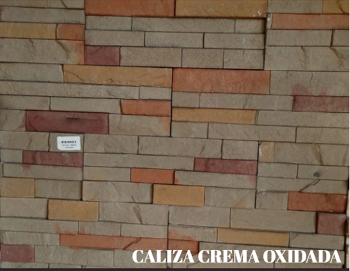 Muro de piedra apilada de colores en tonos beige, tostado y rojo con una pequeña etiqueta que dice “CALIZA CREMA OXIDADA”.