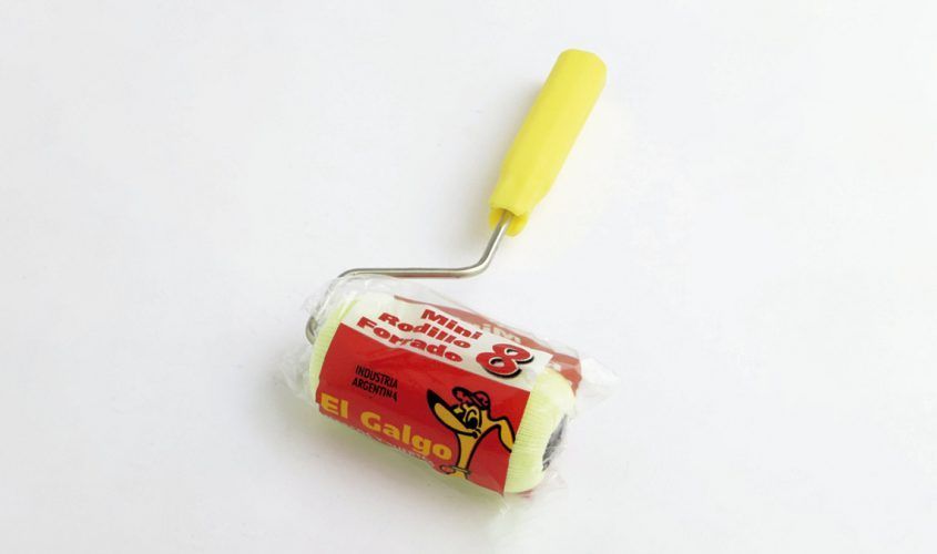Rodillo de pintura con mango amarillo apoyado sobre una pequeña lata de pintura roja y blanca sobre un fondo blanco.
