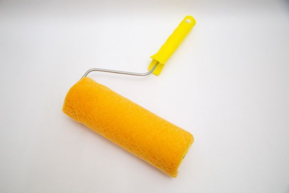 Rodillo de pintura amarillo con mango sobre fondo blanco