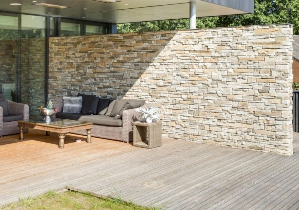 Exterior de una casa moderna revestida de piedra con una gran ventana y césped.