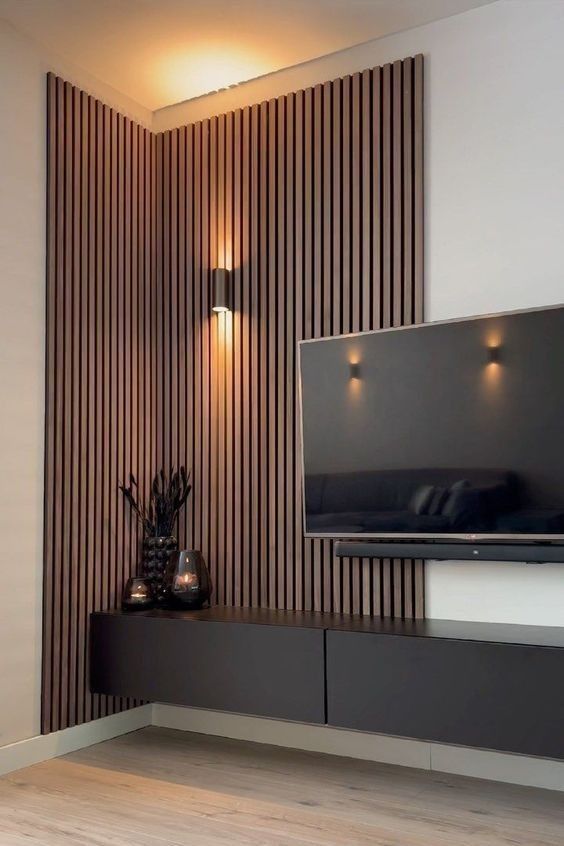 Rincón de sala de estar moderno con listones de madera verticales, apliques de pared, televisor negro
