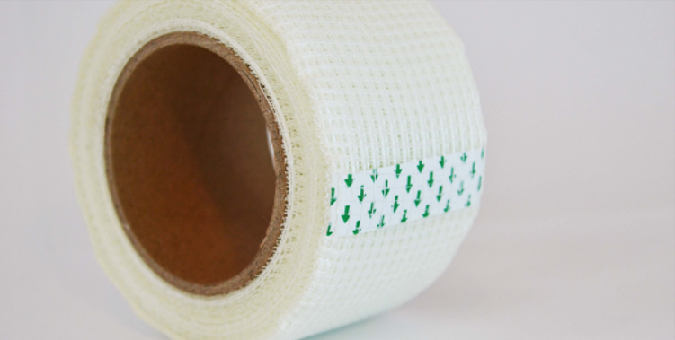 Rollo de venda adhesiva blanca con marcas verdes sobre un fondo liso.