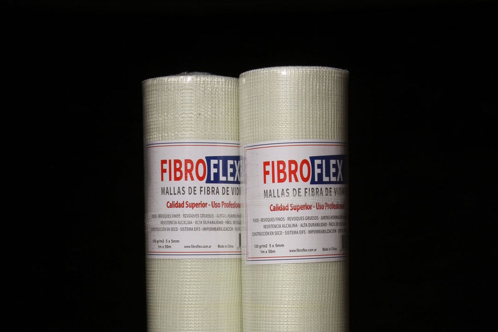 Dos mantas aislantes Fibroflex de color beige enrolladas con etiquetas rojas sobre un fondo negro.