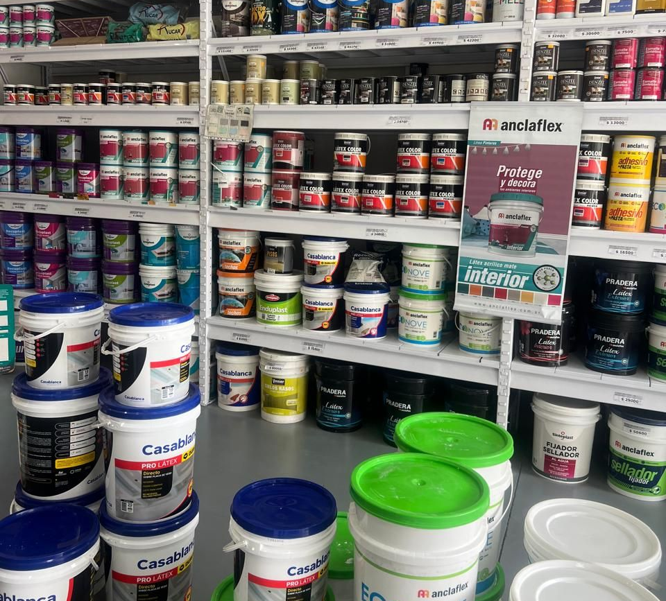 Estanterías repletas de filas de latas y cubos de pintura en una ferretería o tienda de pinturas.