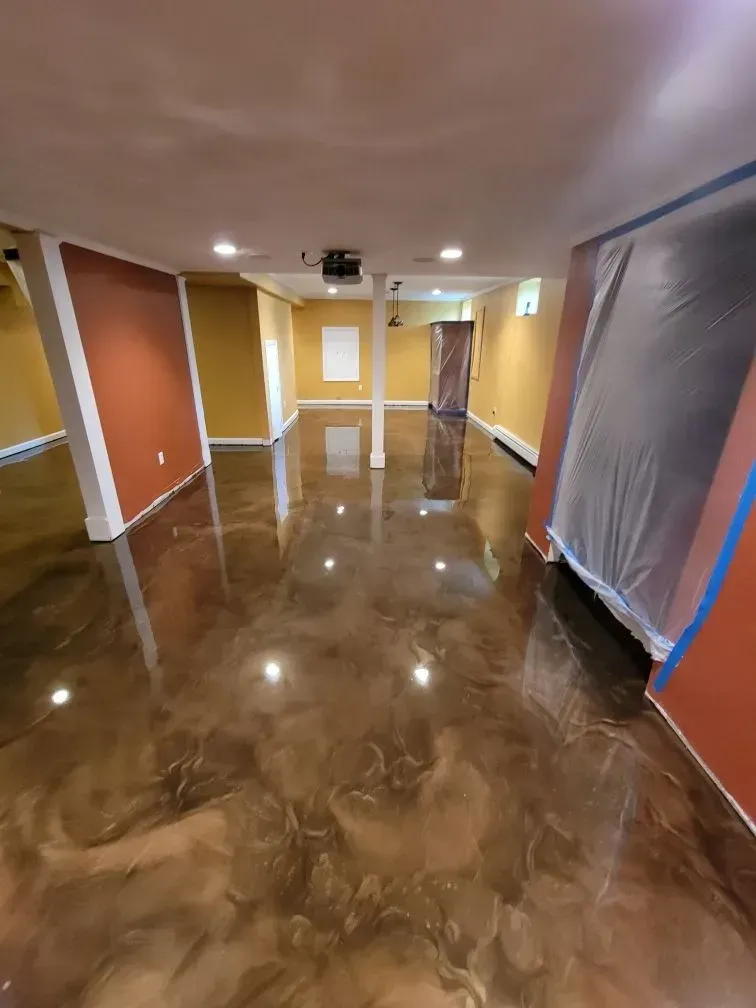 Room with metallic epoxy floor, gold walls, and white columns.