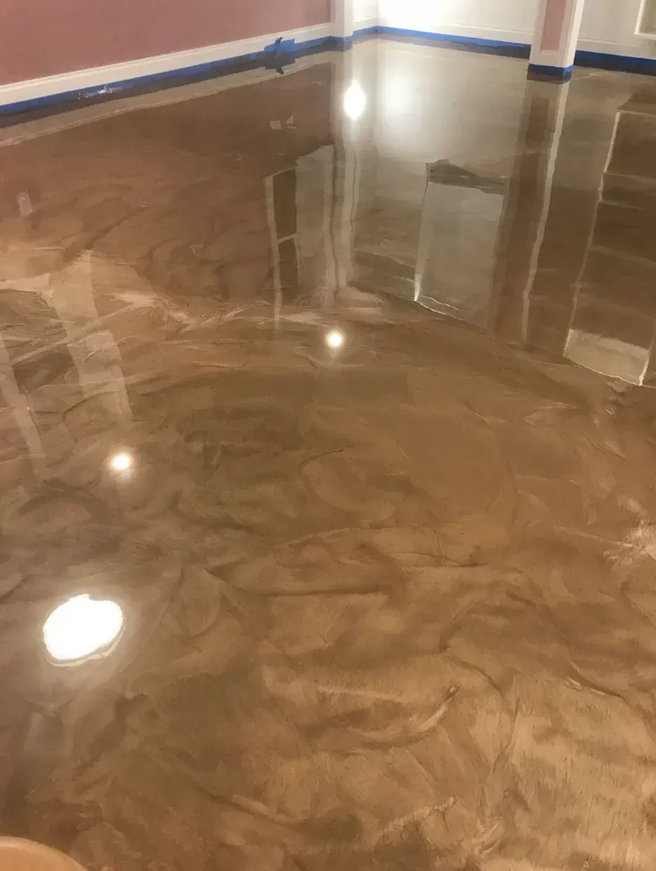Brown and gold metallic epoxy floor. Reflective surface with visible swirls and light reflections.