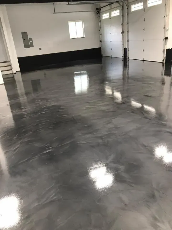 Shiny, grey epoxy floor in a garage with a white door and walls; light reflection.