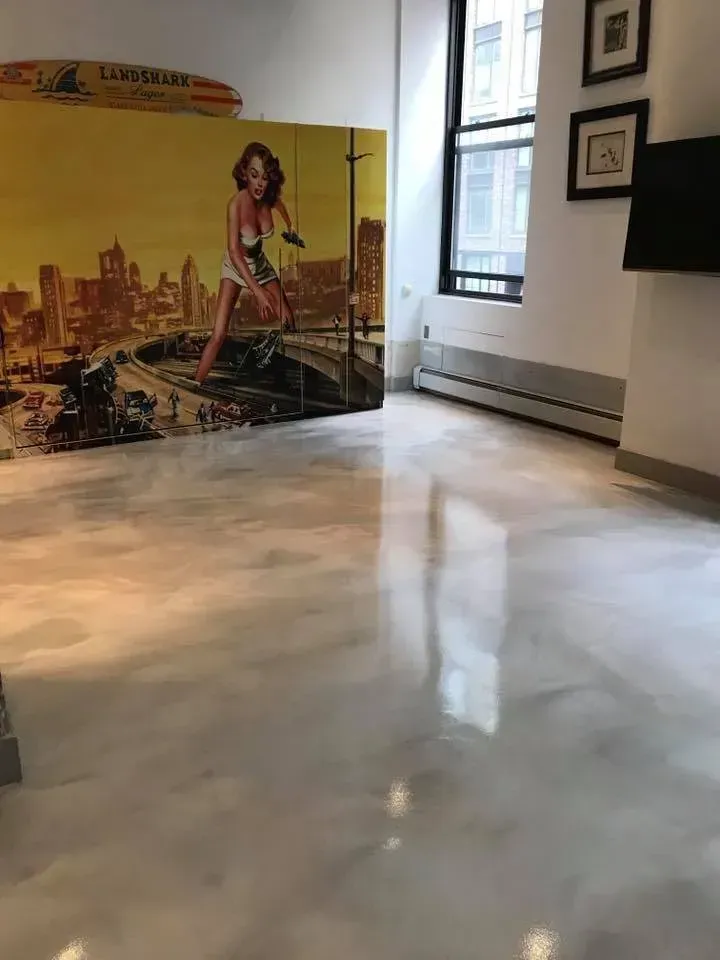 Shiny silver epoxy floor in a room with a cityscape mural and a window.