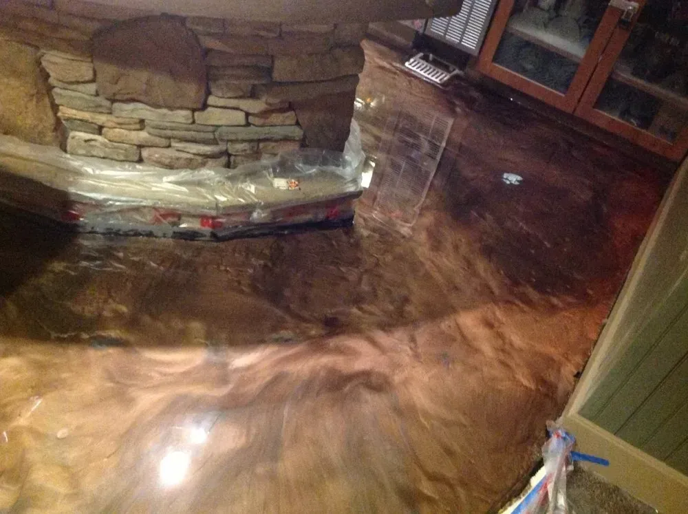 Metallic epoxy floor with swirled patterns and a stone fireplace base.