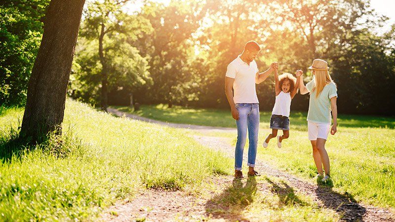 Man and woman swinging young child by her arms