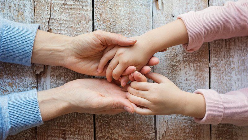 adult holding young child's hands