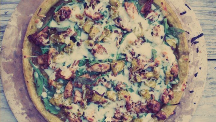 A pizza with a lot of toppings on it is sitting on a wooden table.
