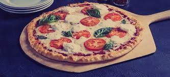 A pizza is sitting on a wooden peel on a table.