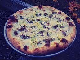 A pizza is sitting on a pan on a table.