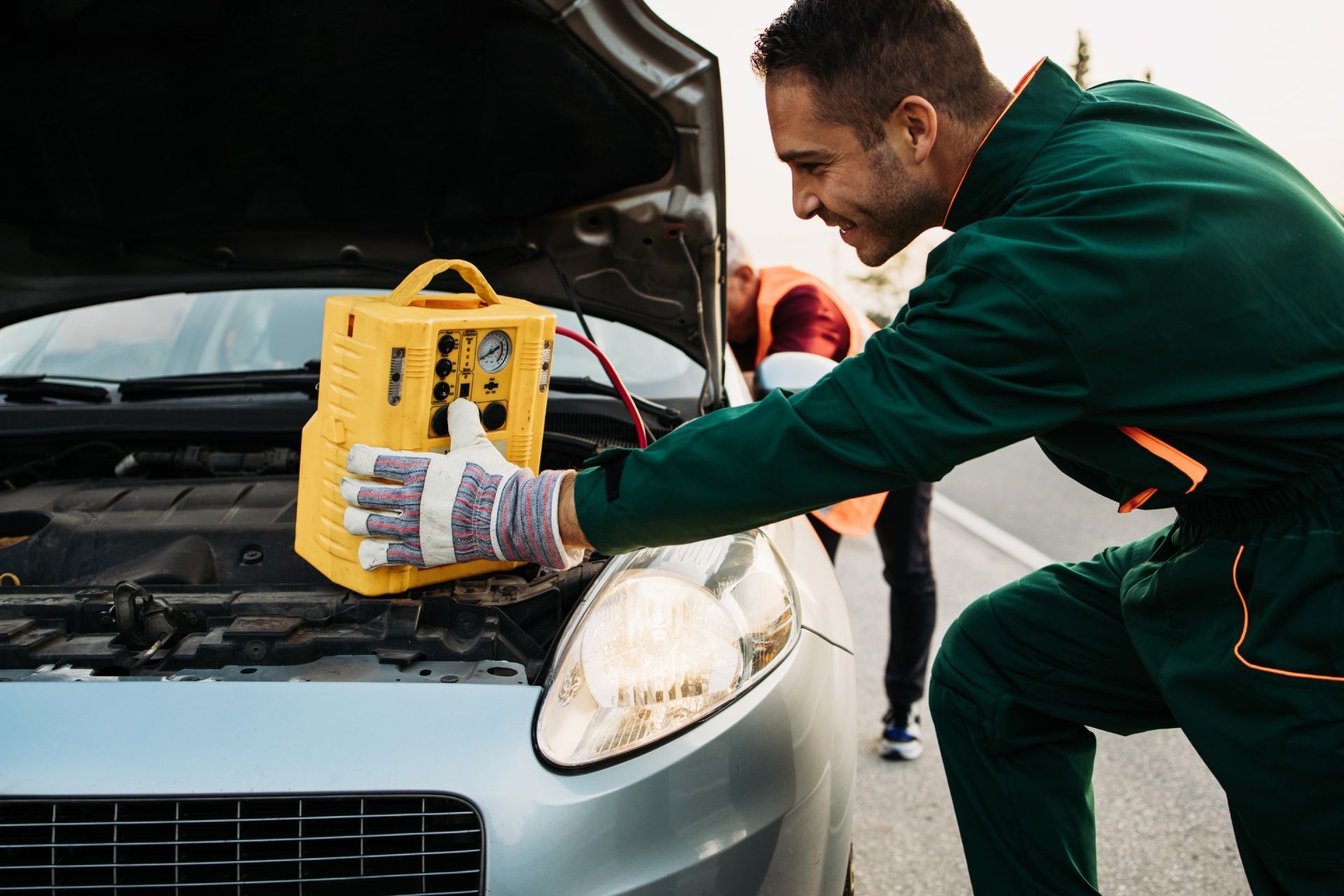 A man is using a jump starter to start a car.