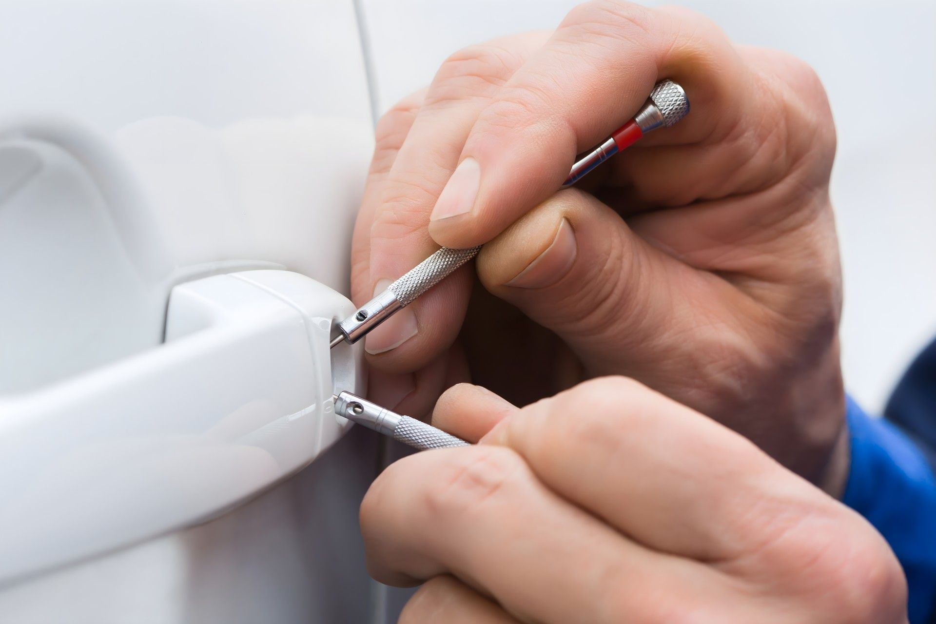 A person is fixing a car door with a screwdriver