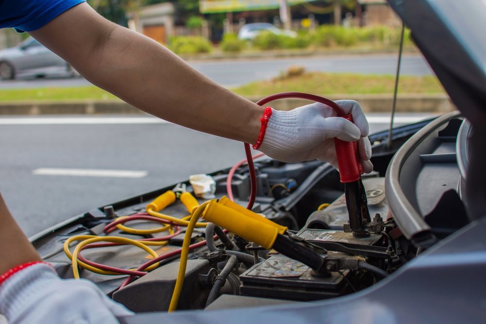 A man is working on a broken down car on the side of the road.