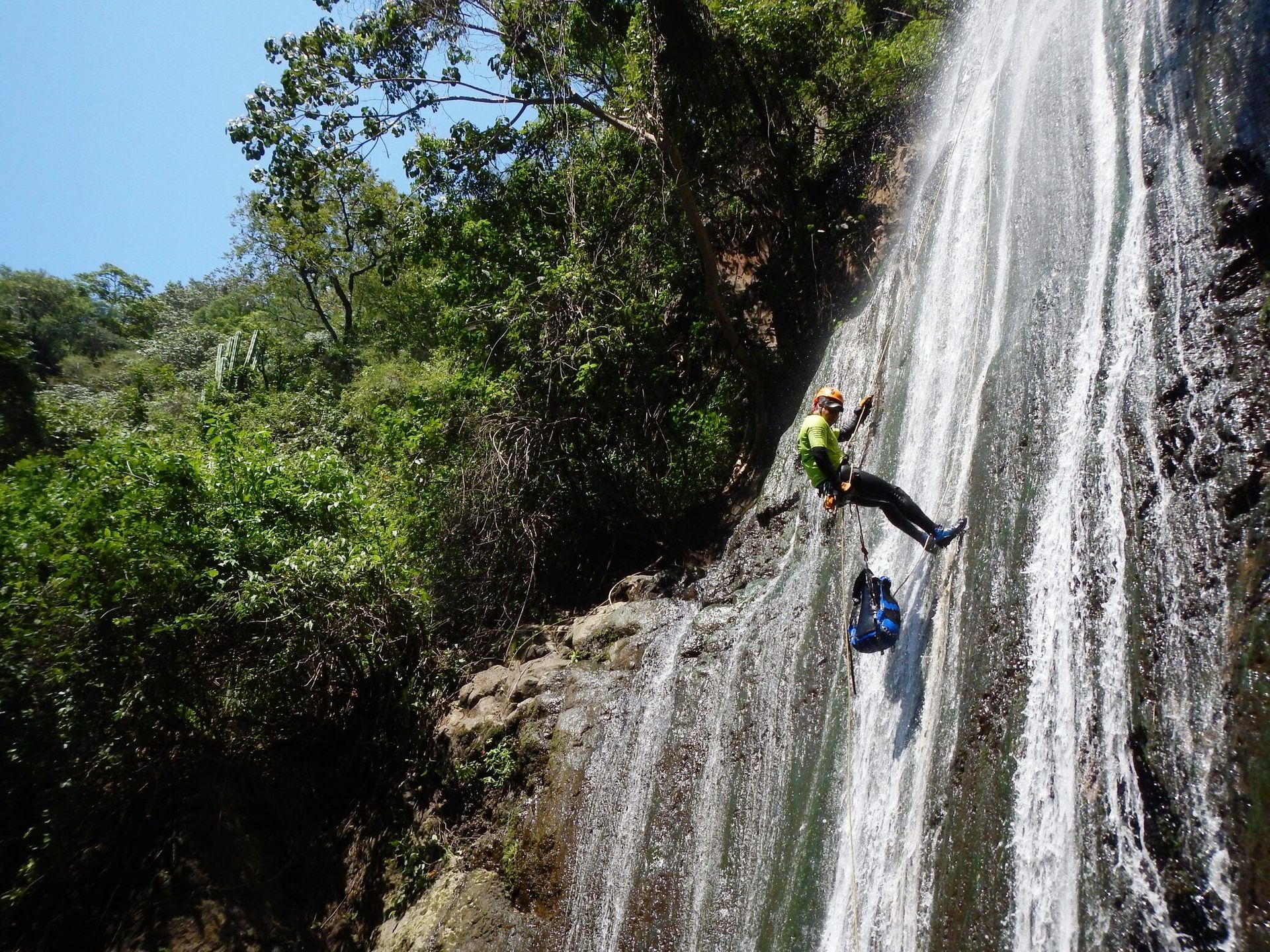 Una persona está escalando una cascada con una mochila.