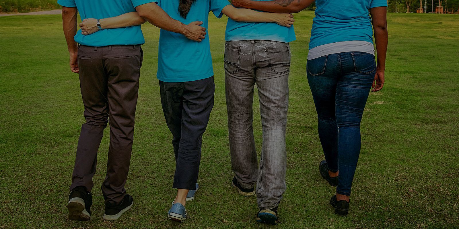 Un grupo de personas camina en un parque abrazados.