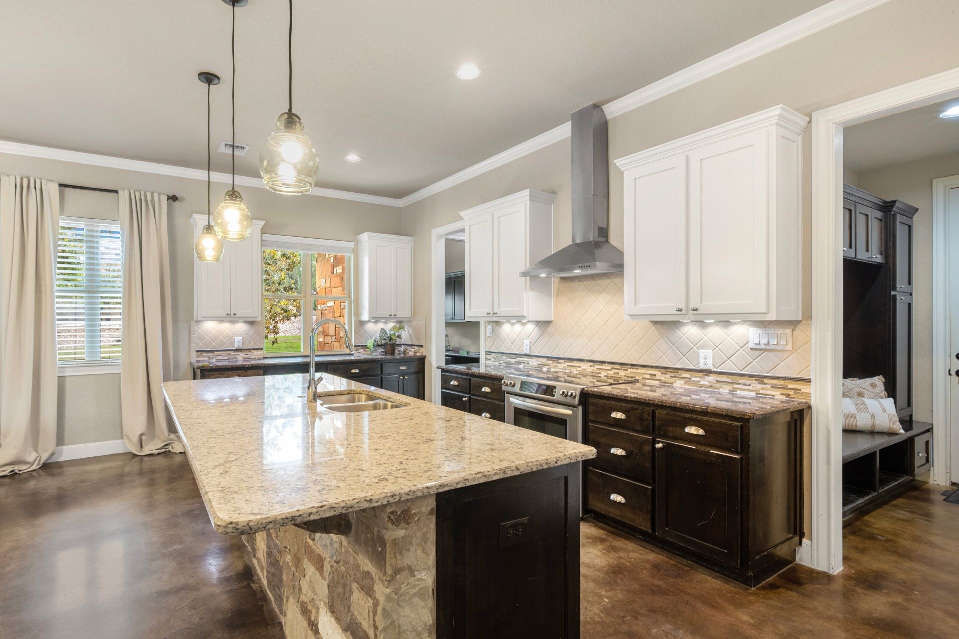 A kitchen with a large island , granite counter tops , white cabinets and stainless steel appliances.