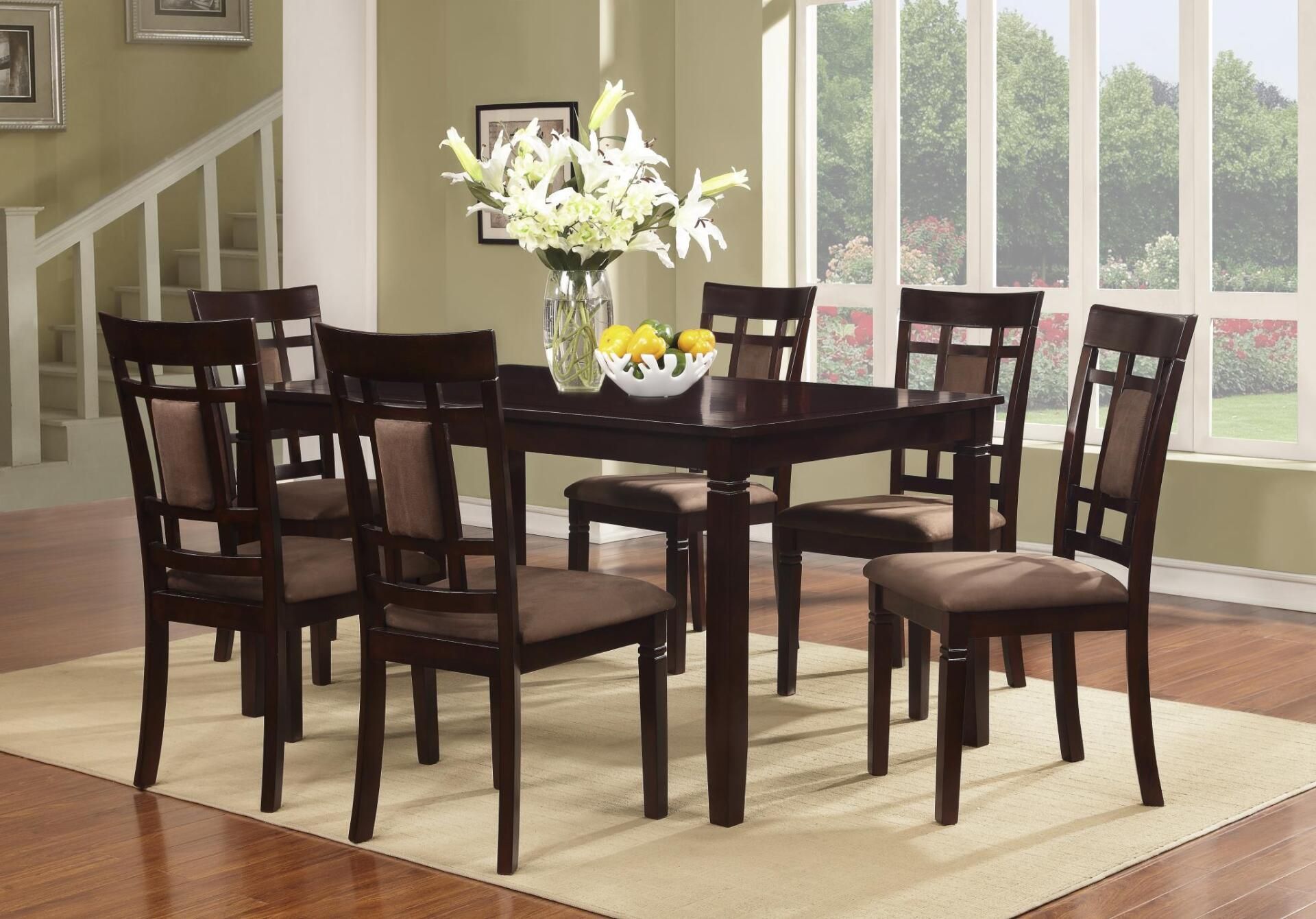A dining room with a table and chairs and a vase of flowers