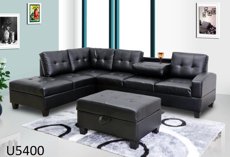 A living room with a black sectional couch and ottoman