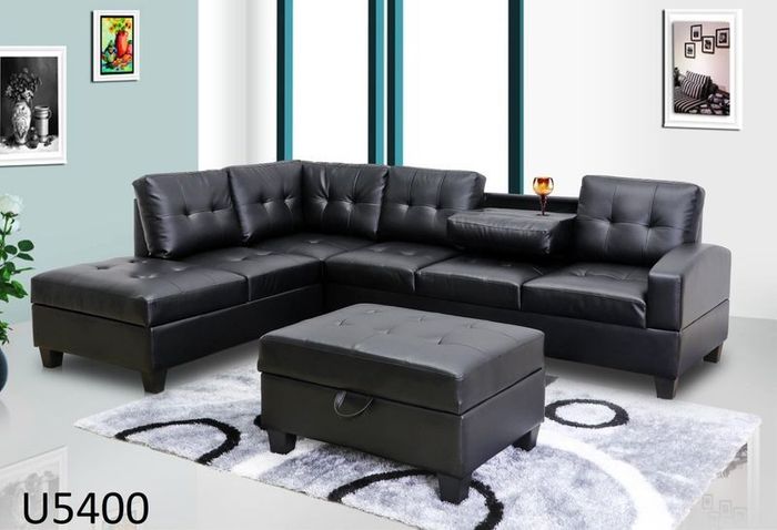 A living room with a black sectional couch and ottoman