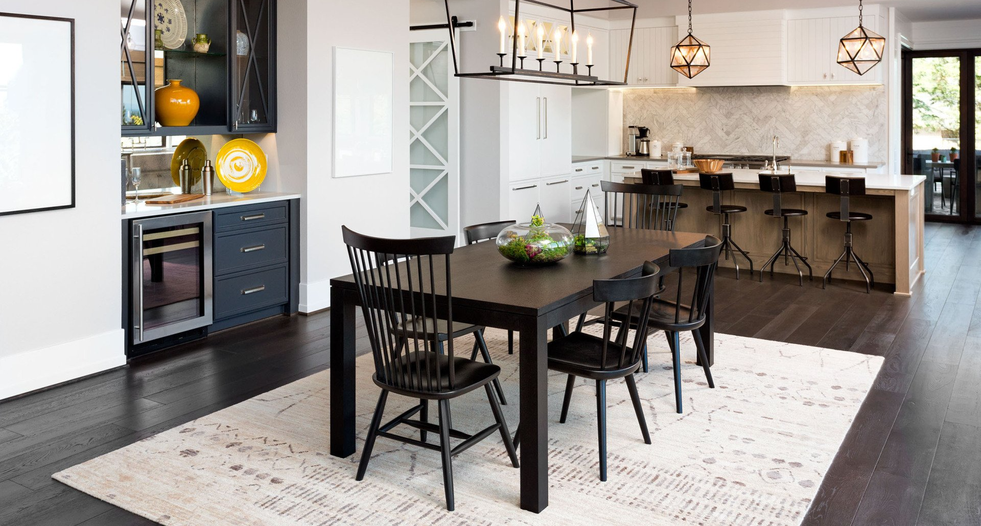 A dining room table and chairs in a kitchen with a rug on the floor.