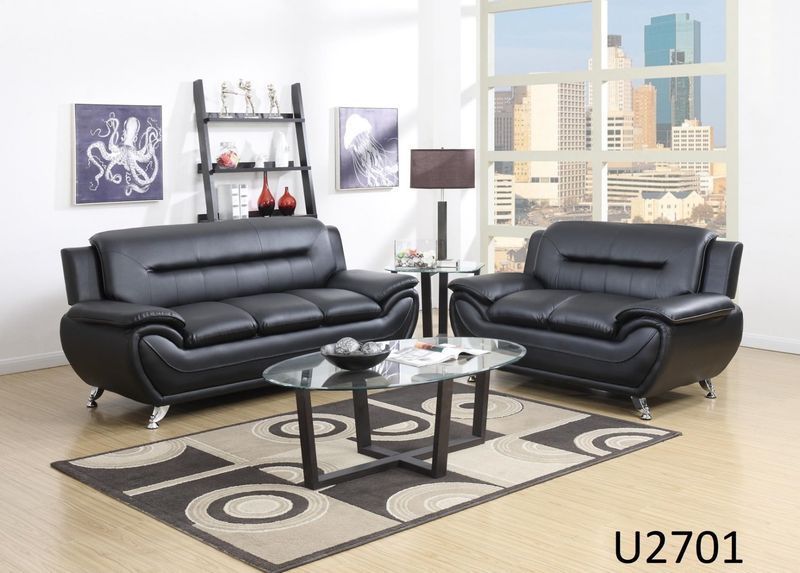 A living room with two black leather couches and a glass coffee table.