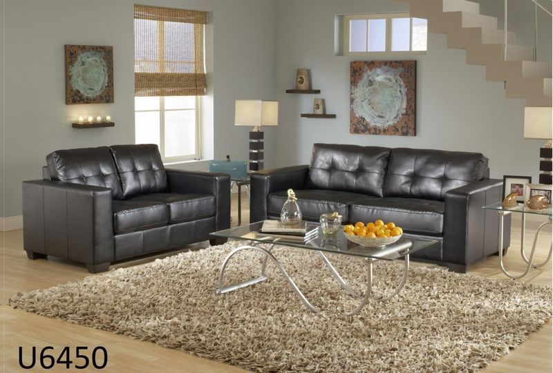 A living room with two black leather couches and a coffee table