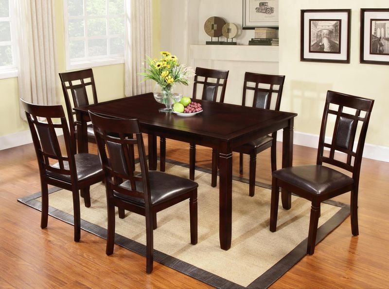 A dining room table and chairs with a vase of flowers on it